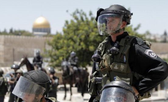 Israeli security looks on as Palestinian Muslim worshipers (unseen) perform traditional Friday noon prayers along a street outside the Old City in East Jerusalem, on July 11, 2014, on the second Friday of Islam's holy month of Ramadan. Israeli authority has forbidden access to Al-Aqsa mosque to Muslim men under 50-years-old. The Dome of the Rock mosque, part of the Al-Aqsa mosque compound, is seen in the background.  AFP PHOTO / AHMAD GHARABLI        (Photo credit should read AHMAD GHARABLI/AFP/Getty Images)