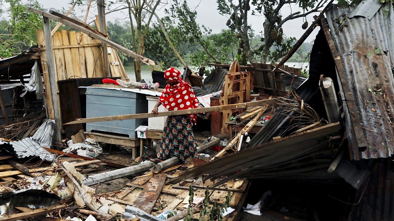 A woman clears her house that was demolished by the cyclone Amphan in Satkhira