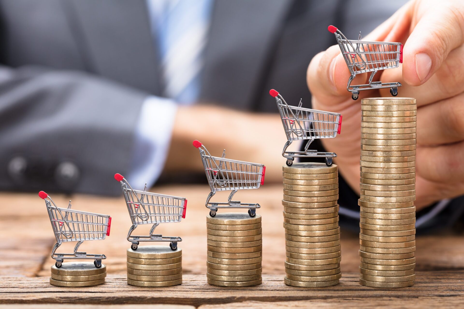 Midsection,Of,Businessman,Placing,Shopping,Cart,On,Stacked,Coins,In